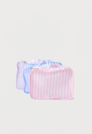 Tre stribede rektangulære toilettasker i pastelpink, blå og lilla, arrangeret side om side på en hvid baggrund.