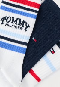 Κάλτσες Tommy Hilfiger: λευκές με μπλε και κόκκινες ρίγες, ναυτικομπλε κάλτσα με ριγωτή υφή, λογότυπο κεντημένο στο μαύρο, με μικρή λεπτομέρεια σημαίας.
