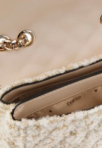 Tweed handbag with a soft cream and gold texture; features a smooth beige leather top and a gold chain accent on the closure.