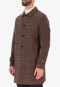 Cappotto in misto lana con motivo a quadri marroni e bottoni neri, colletto ampio e tasche laterali. Presenta una linea dritta e una lunghezza media.