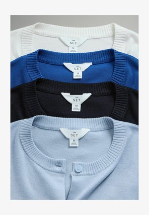 Vier Rundhalsausschnitt-Pullover, übereinandergelegt: weiß, blau, marineblau und hellblau, mit gerippten Kragen und Knopfdetails am hellblauen Pullover.