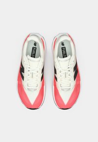 Sportliche Schuhe in Weiß und Koralle, mit einem Obermaterial aus Mesh, schwarzen Logoakzenten und weißen Schnürsenkeln. Leichtes Design mit gepolsterter Sohle.