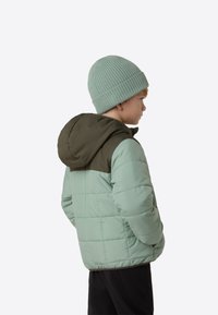 Valgejooneline jope helerohelise tooniga, millel on tumeroheline kapuuts ja horisontaalne pitsiline tekstuur. Komplektis soonikuga mintroheline müts.