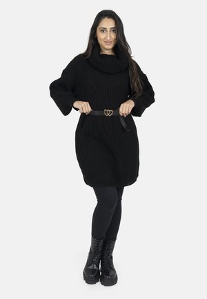 Maglione nero oversize a maglia con colletto a cappuccio, abbinato a una cintura nera con fibbia a forma di cuore, leggings neri e stivali da combattimento con lacci.