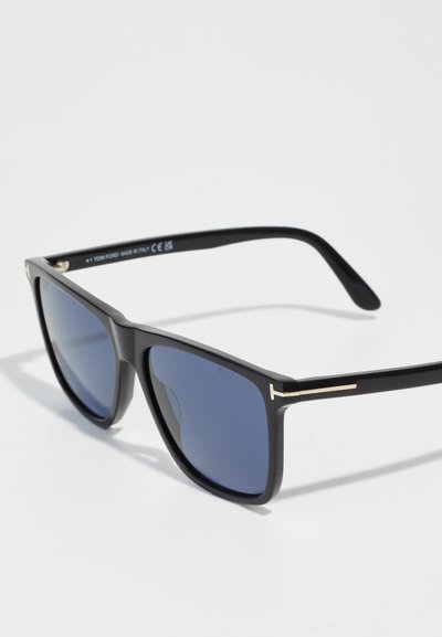 Occhiali da sole in plastica nera con lenti blu scuro, forma quadrata, con accenti dorati sulle astine e dettagli con logo sulla montatura.