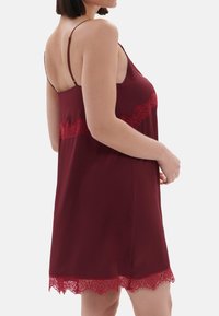 Rochie de noapte din satin bordeaux cu dantelă roșie la talie și margine, având bretele subtiri ajustabile și un design lejer, fluid.