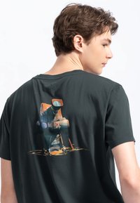 Zwarte katoenen t-shirt met korte mouwen, met een kleurrijke grafische print op de achterkant die een gestileerde vintage camera afbeeldt.