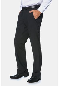 Pantaloni neri, taglio dritto, con tasche frontali, tessuto testurizzato, indossati con una cintura nera e scarpe nere lucidate. Camicia infilata dentro.