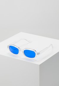 Klare plastik solbriller med blå linser. Oval form, med en robust ramme og tynde arme. Simpelt design uden mønstre eller accenter.