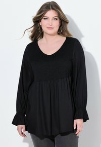 Schwarze Tunika mit V-Ausschnitt, gerafftem Oberteil und langen, ausgestellten Ärmeln. Hergestellt aus weichem Stoff, hat sie eine lockere Passform und eine geraffte Taille.