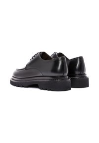 Schwarze Lederschuhe mit glatter Oberfläche, abgerundeter Kappe und dicker Gummisohle mit gezacktem Rand und weißen Nähdetails.