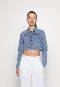 Giacca in denim cropped di colore azzurro chiaro con colletto classico, chiusura a bottoni e due tasche sul petto. Presenta dettagli in bottoni argentati.