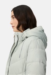 Light gray puffer jacket with a hood, features a zippered front, drawstring accents, and quilted texture. Side profile view.