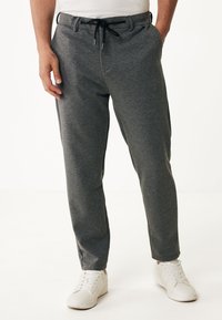 Grijze joggingsbroeken van zachte stof, met een trekkoord in de taille, twee zijzakken en een taps toelopende pijp, gecombineerd met witte sneakers.