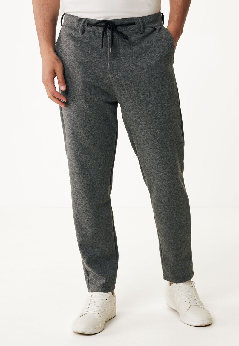 Grijze joggingsbroeken van zachte stof, met een trekkoord in de taille, twee zijzakken en een taps toelopende pijp, gecombineerd met witte sneakers.