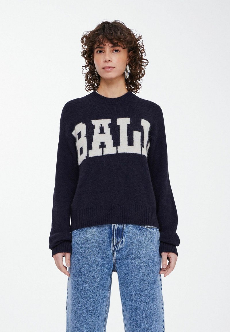 Jūras spēku krāsas adīts džemperis ar krēmkrāsas "BALI" logotipu krūšu daļā; ribinātas piedurknes un apakša; brīvs griezums ar mīkstu tekstūru.