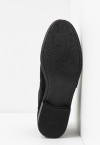 Černá semišová podrážka boty s texturovaným květinovým vzorem, plochým gumovým podpatkem a velikostním označením "37". Hladký povrch s jemnými detaily.