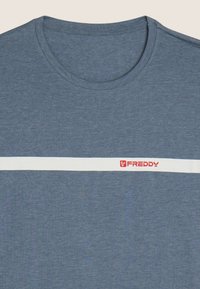 Camiseta de algodón azul con una franja horizontal blanca y el logo "FREDDY" en rojo en el pecho. Corte regular con cuello redondo.