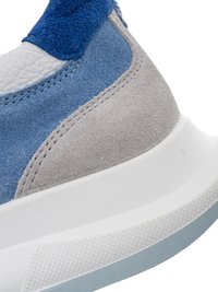 Nahaufnahme der Ferse eines blauen und grauen Wildleder-Sneakers mit weißer Gummisohle und strukturierter Kante.
