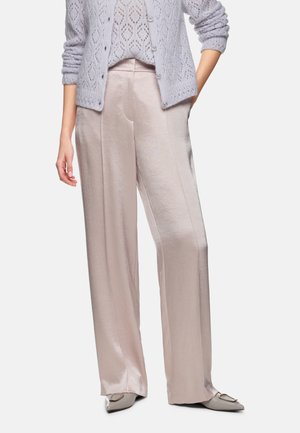 Loose-fitting, pale pink satin trousers featuring a smooth texture, front creases, and a wide leg design. Paired with a knitted lavender cardigan.