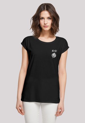 Schwarzes T-Shirt mit hochgerollten Ärmeln, das ein silbernes AC/DC-Logo und ein Blitzgrafik auf der Brust zeigt, aus weichem Baumwollmaterial gefertigt.