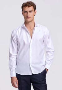 Witte langwerpige overhemd met lange mouwen in een soepele stof met een klassieke kraag en manchetten met één knoop, voorzien van een subtiele glans en een getailleerd ontwerp.