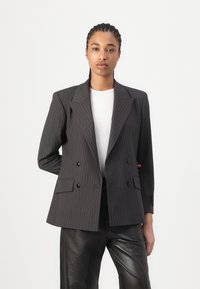 Šedý pruhovaný dvouřadý blazer, strukturovaný silueta, klopové límce, přední kapsy, spárovaný s bílým topem a černými kalhotami.