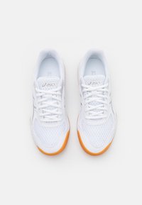 Pari valkoisia Asics-juoksukenkiä oransseilla pohjilla nähtynä ylhäältä valkoisella taustalla.