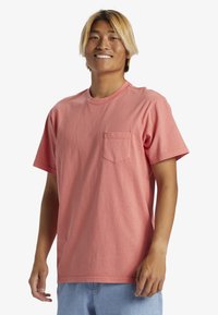 Krátký rukáv, korálová bavlněná tričko s kulatým výstřihem a kapsou na prsou; uvolněný střih a hladká textura, vhodné pro každodenní nošení.