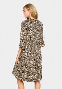 Rochie cu imprimeu leopard, cu un design în straturi, mâneci volănaș și material moale. Culorile bej și negru predomină în model, având o croială lejeră.