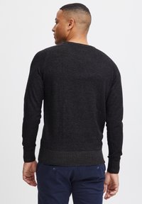 Donkergrijze lange mouwen trui met een ronde hals, ribgebreide manchetten en zoom, met een textuur gebreid patroon. Vijf subtiele stretch en een aansluitend ontwerp.
