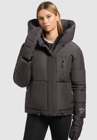 Ullig, mörkgrå jacka med stor huva, dragkedja fram i fickan och elastiska ärmar. Har ett texturerat tyg och snörning i nederkant.