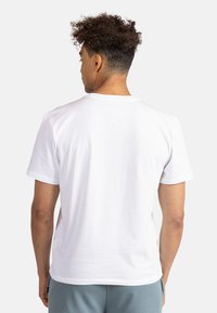 Camiseta blanca de algodón con mangas cortas y cuello redondo, mostrando la vista trasera. Textura suave con un diseño simple y limpio.