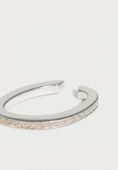 Ασημένιο ανοιχτό βραχιόλι με μια σειρά από μικρούς λαμπερούς κρύσταλλους κατά μήκος της εξωτερικής άκρης, απεικονίζεται σε λευκό φόντο.