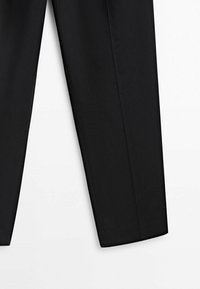 Pantalon de costume noir sur mesure avec plis marqués à l'avant, présenté à plat sur fond blanc.