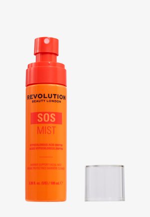 Flacon spray orange étiqueté Revolution Beauty London SOS Mist avec un bouchon transparent posé à côté sur fond blanc.