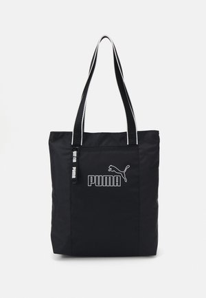 Czarna torba typu tote marki Puma z dwoma długimi czarno-białymi paskami, przednią kieszenią na zamek i logo Puma nadrukowanym na biało.