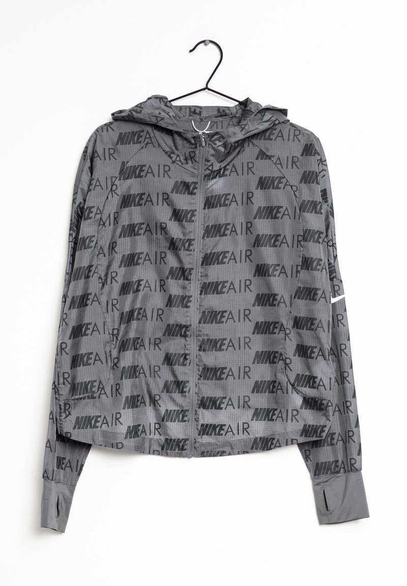 Veste légère à capuche Nike Air grise avec fermeture éclair intégrale à l’avant et motif de logo noir, suspendue sur un cintre noir sur fond blanc.