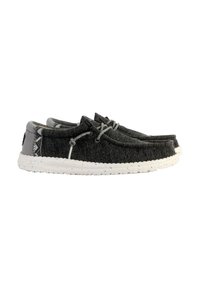 Zapatos de tela grises tipo slip-on con punta redonda, suela blanca moteada y detalles texturizados en el talón. Cordonera ajustable para un ajuste seguro.