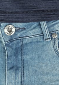 Light blue denim jeans with a silver button featuring "Gabbiano" embossed, and dark blue ribbed waistband detail.