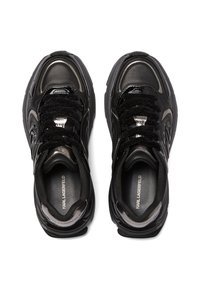 Melni sporta apavi ar spīdīgu virsmu, faktūrētām auduma šņorēm un sudraba akcentiem; ir ar mīkstu apkakli un logotipu uz zoles.