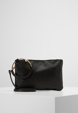 Czarna teksturowana kopertówka na nadgarstek z złotym okrągłym uchwytem i odpinanym paskiem, umieszczona na białej powierzchni na tle jednolitego szarego tła.