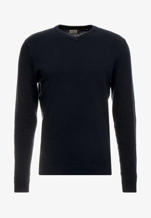 Tamsiai mėlynas megztinis, V formos iškirpte, ilgomis rankovėmis, raukšlėtais rankogaliais ir apačia, lygus audinys, lengvas audinys, paprastas dizainas be raštų ar puošmenų.