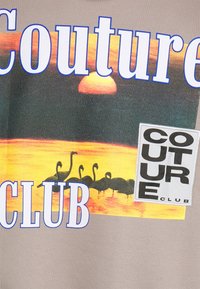 Grafické tričko s motivem západu slunce nad vodou a siluetami ptáků, text "Couture Club" v modré barvě a čtvercová nášivka s logem.