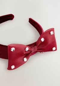 Maroon samettipanta, jossa on satiininen ruusu, jossa on kuusi kirkasta strassikiveä valkoisella pinnalla.