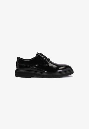 Chaussure habillée noire en cuir brillant à lacets, semelle épaisse, petit talon et bout arrondi, vue de côté extérieure sur fond blanc.