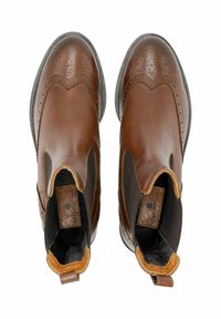 Stivali ankle in pelle marrone con una finitura liscia, pannelli laterali elastici, perforazioni decorative e un accento di tallone tan a contrasto.