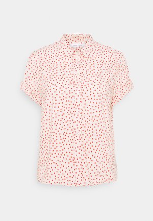 Korte mouwen shirt van lichtroze stof, met een knoopsluiting aan de voorkant, met een patroon van rode stippen overal. Fijne textuur.