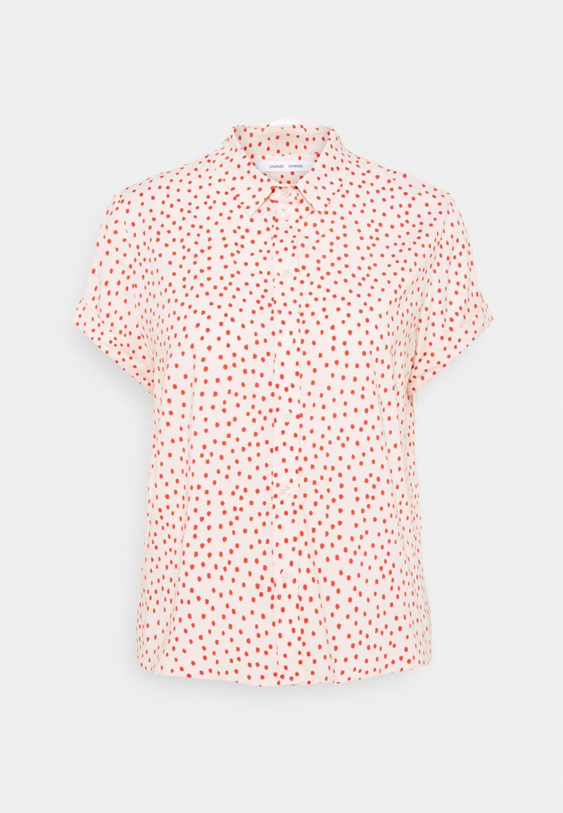 Chemise à manches courtes en tissu rose clair, avec un devant à boutons, ornée d'un motif de pois rouges partout. Texture lisse.