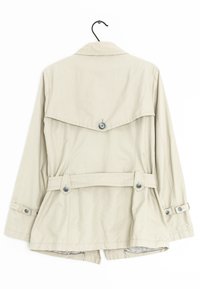 Giacca beige, leggera, con vita regolabile, grande pattina sul retro e dettagli con bottoni, dotata di maniche lunghe e orlo dritto.